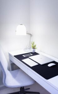 Aménagement de bureau à domicile élégant et moderne comprenant des appareils Apple, une lampe de bureau et une plante.