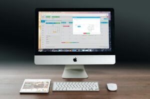 Un bureau élégant comprenant un Apple iMac, un iPad et un clavier sur un bureau en bois.