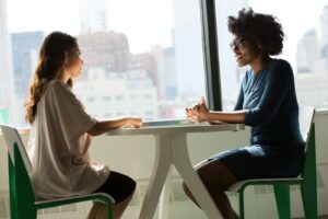 deux femmes assises à côté d'une table et discutant
